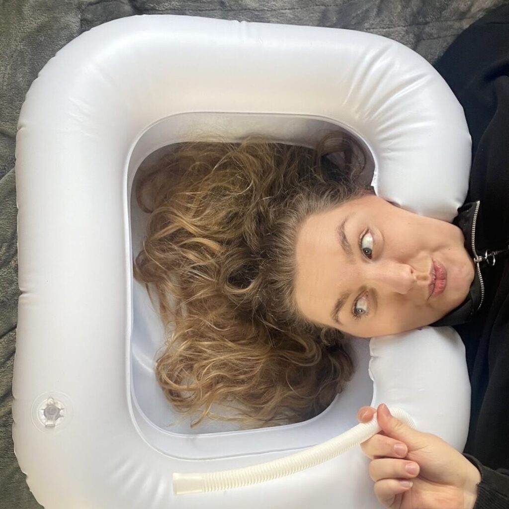Photo of a woman testing out a inflatable shampoo basin bathroom aid.
