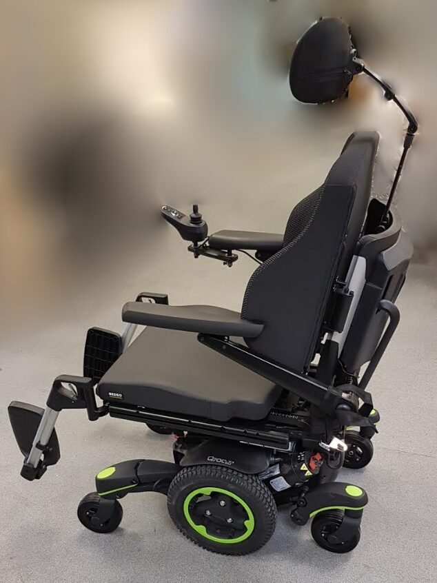 Side profile photo of a 'Quickie Jive M' with its large front & back castors, headrest that is separated from the backrest, are all visible.