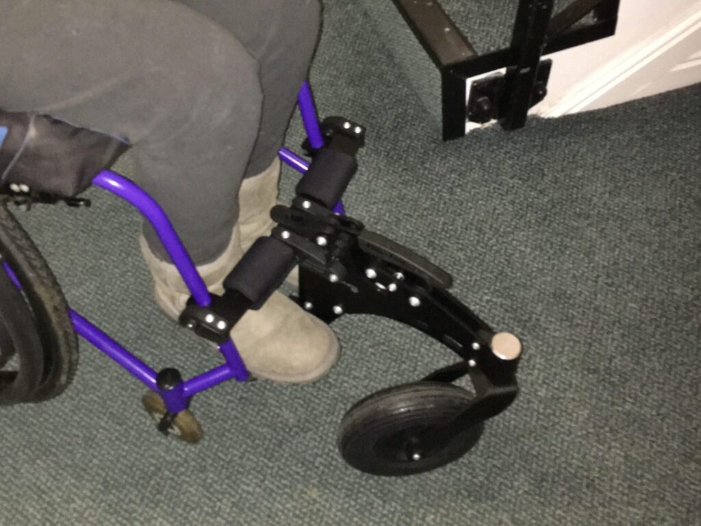 Photo of a 'RGK Maxlite' self-propelling wheelchair with an 'RGK Frontwheel' connected to the wheelchair just above the footrests.