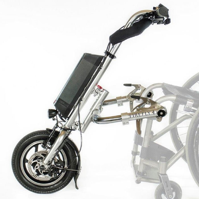 Side profile image of a 'Rio Firefly 2.0' bike-style power assist add-on. A faint image of a wheelchair shows how the add-on connects to the wheelchair when in use.