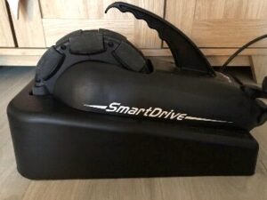 Photo of a 'SmartDrive' power add-on for a wheelchair, in a storage container when not in use.