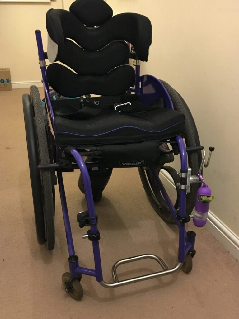 Profile photo of a self-propelling wheelchair with 'SmartDrive MX2+' power assist device, connected to the rear of the wheelchair.