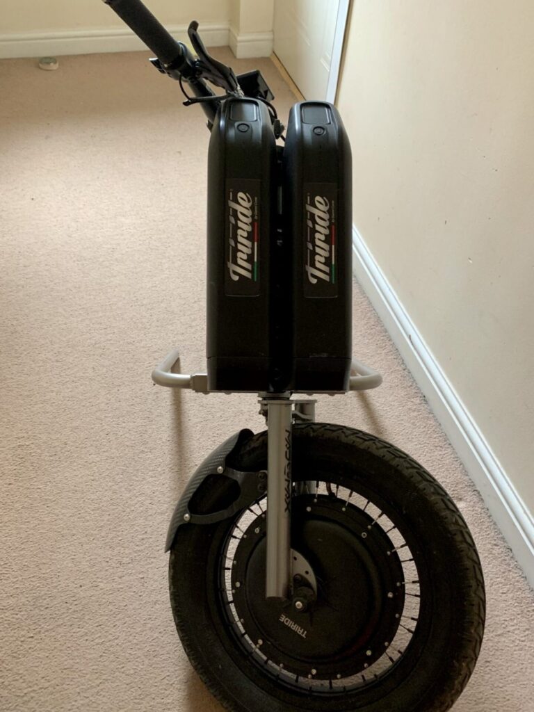 Profile photo of a 'Triride Mad Max' bike-style power attachment, leaning at an angle, due to it not being connected to a wheelchair.