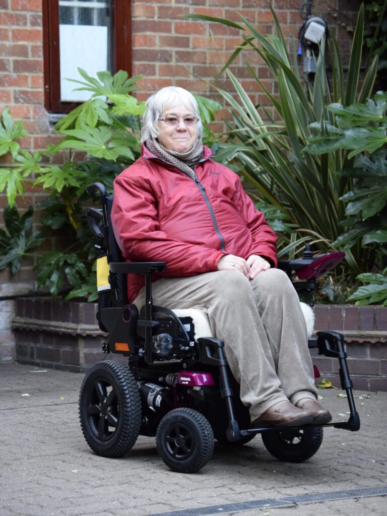 Photo of an older woman using a black & purple frame 'Ottobock B5'.