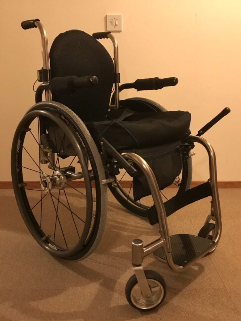 Three quarter profile photo of a black 'RGK Ti-Lite' self-propelling wheelchair.